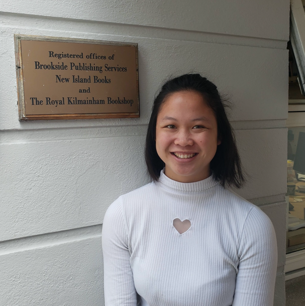 Woman smiling in front of New Island Books & Brookside Publishing Services plaque.