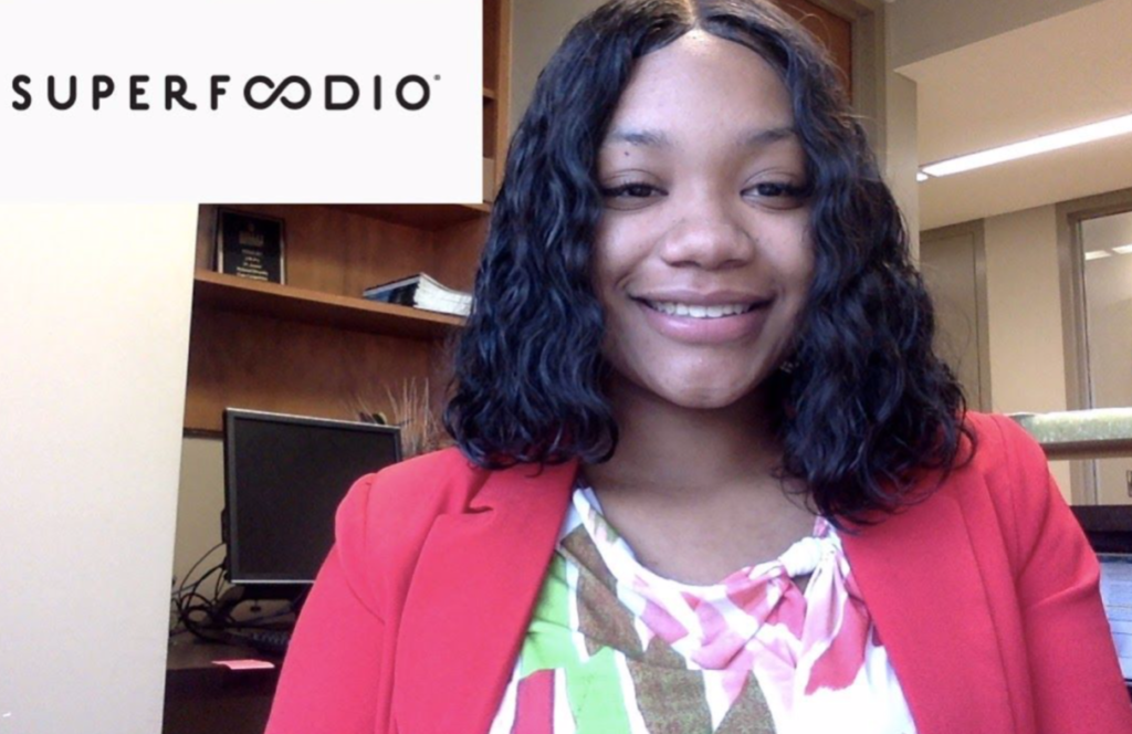 Woman in pink blazer smiling at camera with a Superfoodio logo in the upper left hand corner.