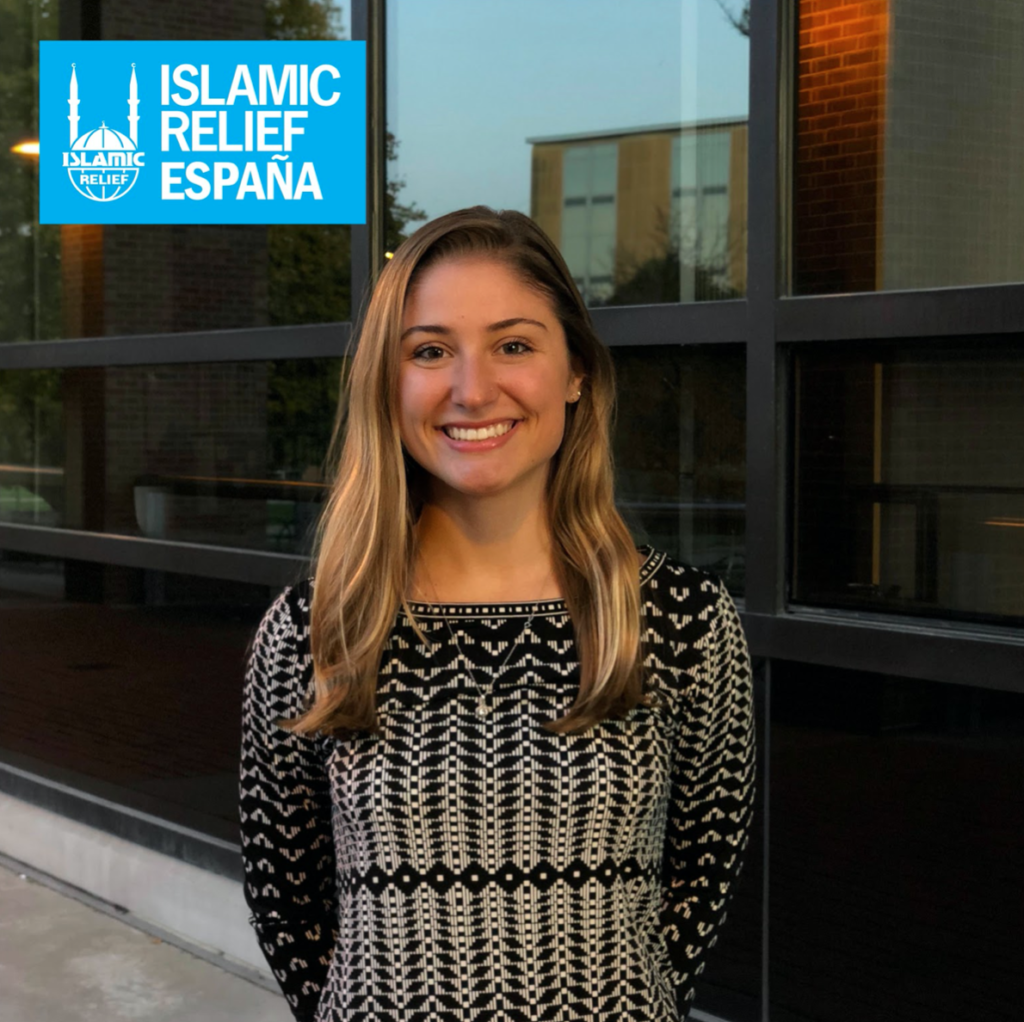 Woman smiling at camera in black and white patterned shirt with Islamic Relief España logo in upper left corner.